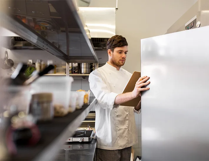 Chef looking inside commercial refrigerator.